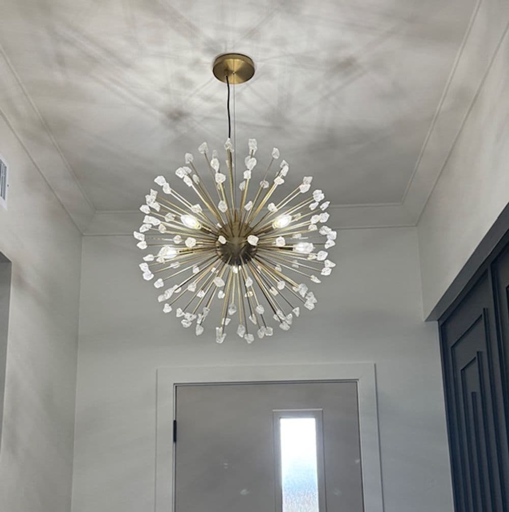 Modern starburst chandelier with golden accents illuminating a hallway.